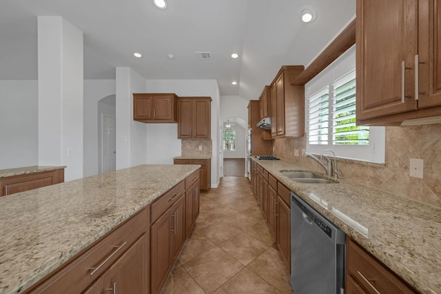 20700 Windmill Ridge St, Pflugerville, TX 78660 - kitchen with stainless steel appliances, backsplash, light stone countertops, brown cabinetry, and arched walkways