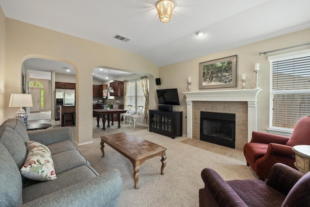 11208 Persimmon Gap Dr, Austin, TX 78717 - living area with arched walkways, light colored carpet, a tile fireplace, and vaulted ceiling