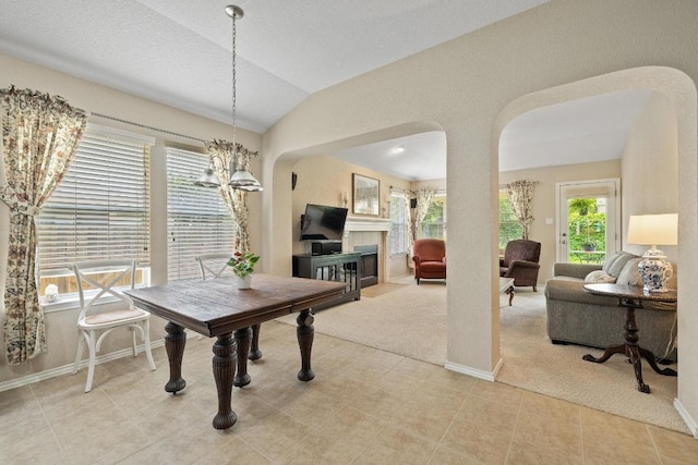 11208 Persimmon Gap Dr, Austin, TX 78717 - dining room featuring arched walkways, a fireplace, vaulted ceiling, carpet floors, and baseboards