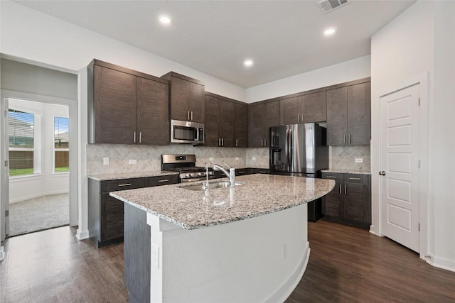 605 Bridle Creek Dr, Georgetown, TX 78626 - kitchen featuring stainless steel appliances, dark brown cabinets, a sink, dark wood-style flooring, and a center island with sink