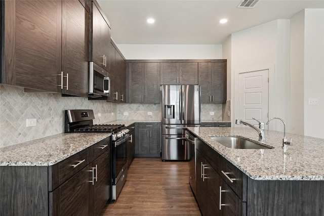 605 Bridle Creek Dr, Georgetown, TX 78626 - kitchen with stainless steel appliances, a sink, dark brown cabinets, dark wood finished floors, and a kitchen island with sink