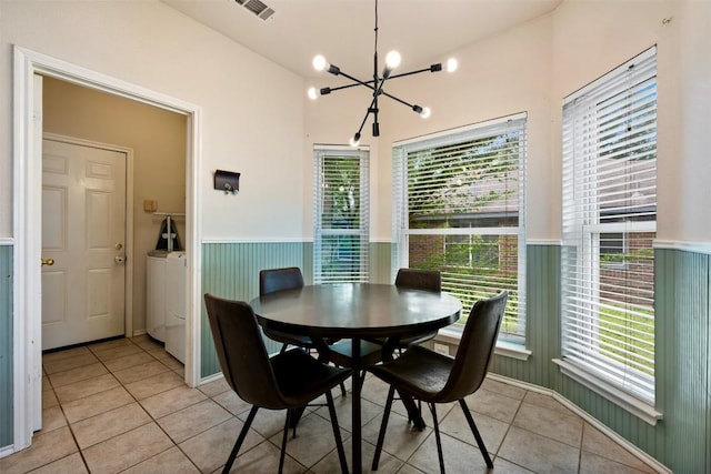 17121 Bishopsgate Dr, Pflugerville, TX 78660 - dining room with light tile patterned flooring, a chandelier, a wainscoted wall, and separate washer and dryer