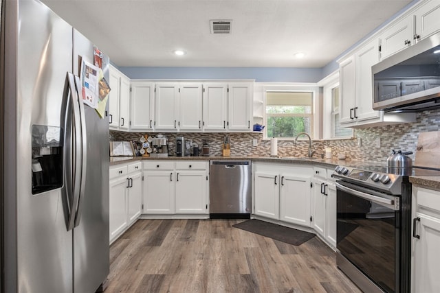 1250 S Rainbow Ranch Rd, Wimberley, TX 78676 - kitchen with appliances with stainless steel finishes, a sink, dark wood-style floors, white cabinets, and decorative backsplash