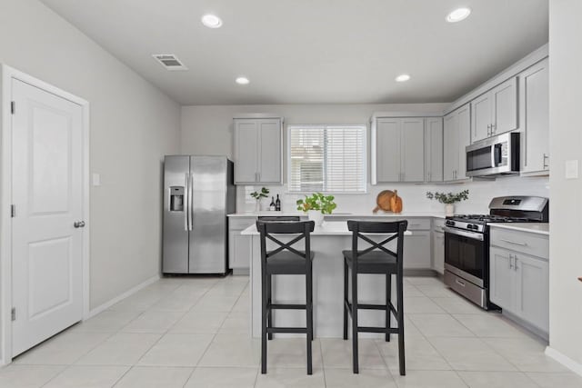 299 Fabion St, Kyle, TX 78640 - kitchen with appliances with stainless steel finishes, gray cabinets, light countertops, a breakfast bar area, and recessed lighting