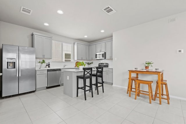 299 Fabion St, Kyle, TX 78640 - kitchen with appliances with stainless steel finishes, gray cabinets, a kitchen breakfast bar, light countertops, and recessed lighting