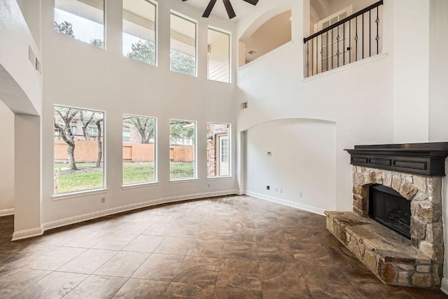 9812 Whitley Bay Dr, Austin, TX 78717 - unfurnished living room with healthy amount of natural light, a high ceiling, a ceiling fan, a stone fireplace, and baseboards