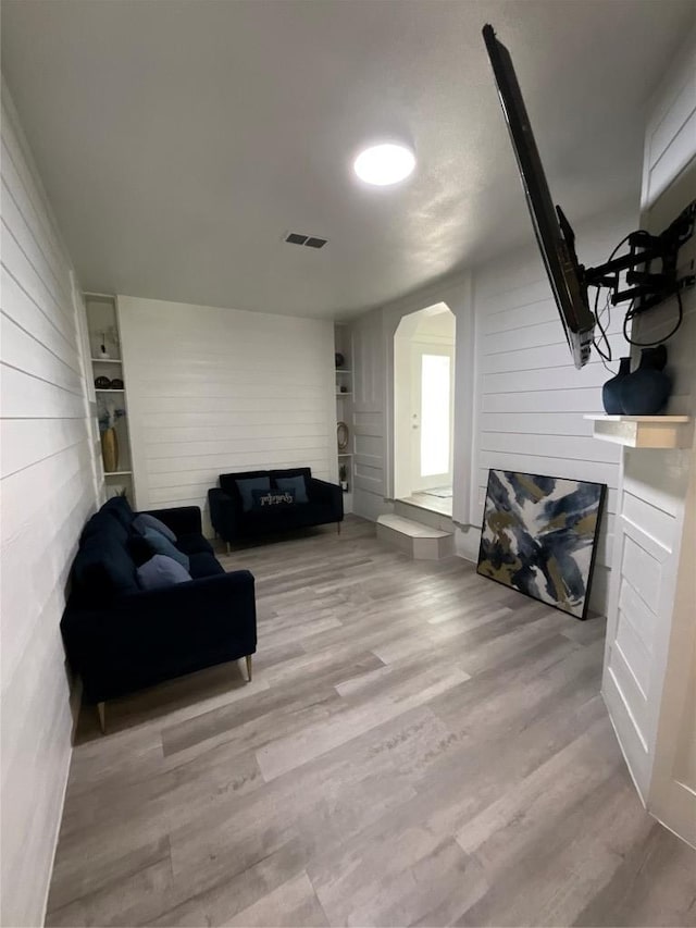 14902 Nuttall Dr, Austin, TX 78724 - living area featuring a glass covered fireplace, wooden walls, wood finished floors, and arched walkways