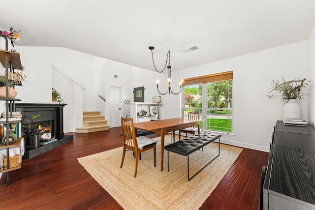 11542 Gun Fight Ln, Austin, TX 78748 - dining area with dark wood-style floors, a warm lit fireplace, stairs, a chandelier, and baseboards