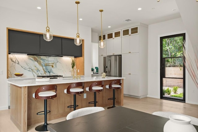 517 Tillery St Unit 3, Austin, TX 78702 - kitchen featuring stainless steel fridge, decorative backsplash, light countertops, an island with sink, and glass insert cabinets