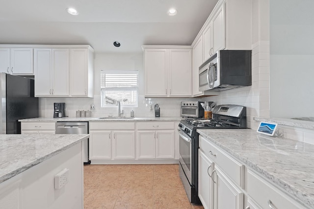 3712 Brean Down Rd, Pflugerville, TX 78660 - kitchen with stainless steel appliances, white cabinetry, decorative backsplash, light stone countertops, and recessed lighting