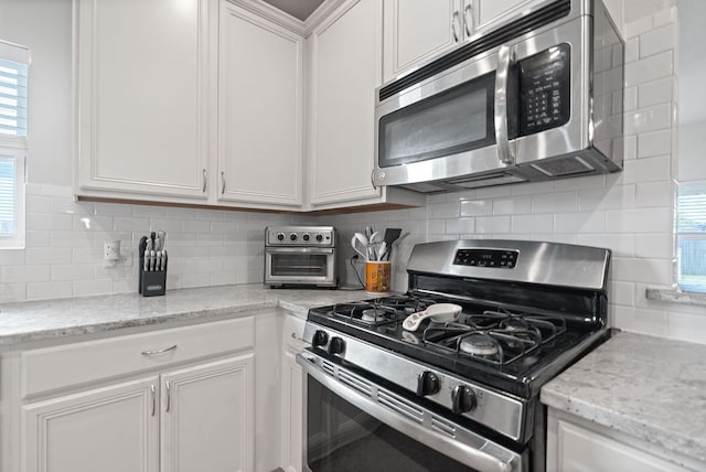 3712 Brean Down Rd, Pflugerville, TX 78660 - kitchen with appliances with stainless steel finishes, white cabinets, plenty of natural light, and backsplash