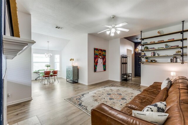 205 Tolcarne Dr, Hutto, TX 78634 - living room featuring wood finished floors, a chandelier, vaulted ceiling, a ceiling fan, and baseboards