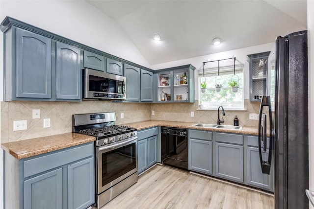 205 Tolcarne Dr, Hutto, TX 78634 - kitchen featuring black appliances, a sink, lofted ceiling, light wood finished floors, and tasteful backsplash