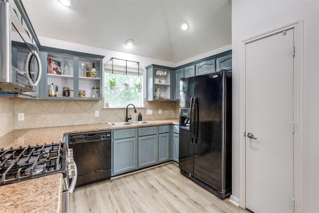 205 Tolcarne Dr, Hutto, TX 78634 - kitchen with black appliances, open shelves, light wood-style floors, light countertops, and lofted ceiling