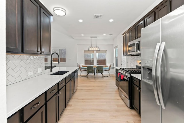 6010 Principale Dr, Pflugerville, TX 78660 - kitchen with appliances with stainless steel finishes, a sink, light wood-type flooring, backsplash, and recessed lighting