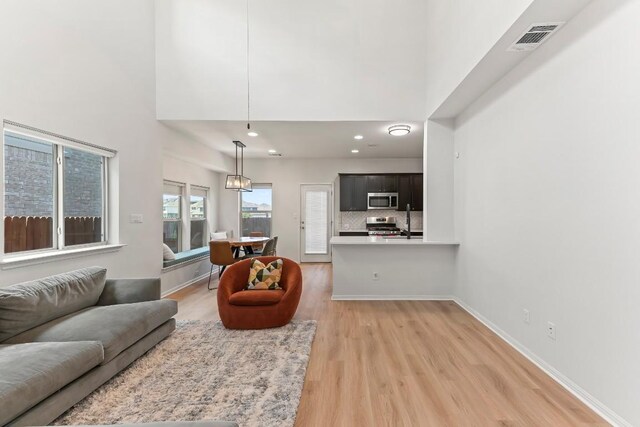 6010 Principale Dr, Pflugerville, TX 78660 - living room featuring light wood finished floors, a high ceiling, baseboards, and recessed lighting