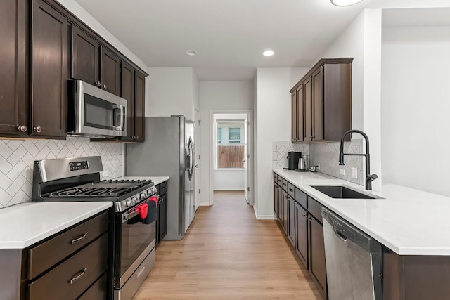 6010 Principale Dr, Pflugerville, TX 78660 - kitchen with appliances with stainless steel finishes, a sink, dark brown cabinets, light wood finished floors, and recessed lighting