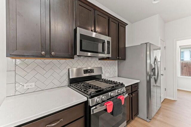 6010 Principale Dr, Pflugerville, TX 78660 - kitchen featuring appliances with stainless steel finishes, dark brown cabinets, tasteful backsplash, light countertops, and light wood-style floors