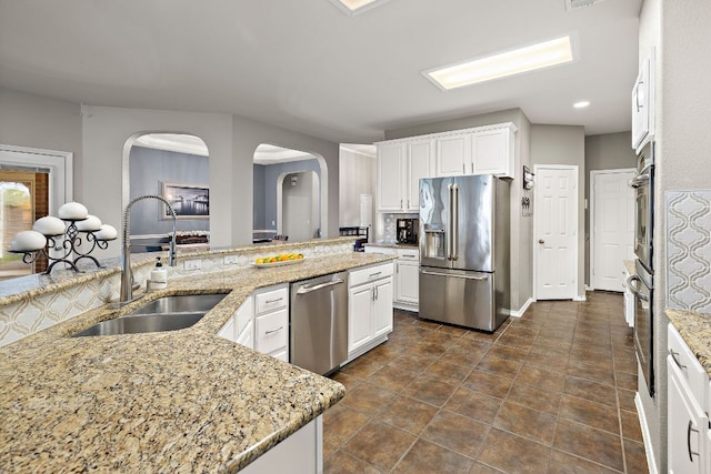 1518 Foppiano Loop, Round Rock, TX 78665 - kitchen featuring appliances with stainless steel finishes, a sink, arched walkways, white cabinets, and recessed lighting