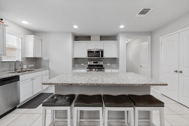 2211 Bettylou Ln, Austin, TX 78754 - kitchen with appliances with stainless steel finishes, a kitchen bar, a sink, decorative backsplash, and recessed lighting