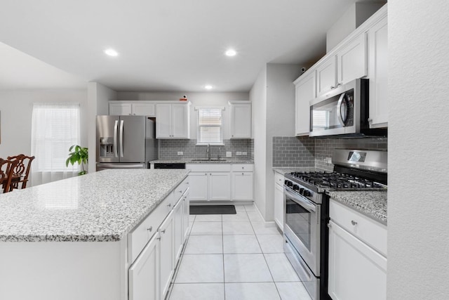 2211 Bettylou Ln, Austin, TX 78754 - kitchen featuring appliances with stainless steel finishes, a sink, decorative backsplash, a kitchen island, and white cabinetry