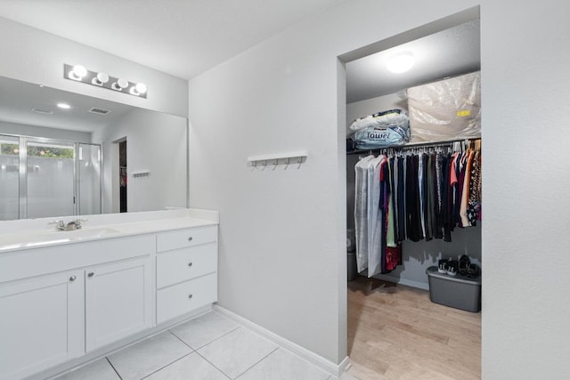 2211 Bettylou Ln, Austin, TX 78754 - bathroom featuring a spacious closet, vanity, a stall shower, wood finished floors, and baseboards