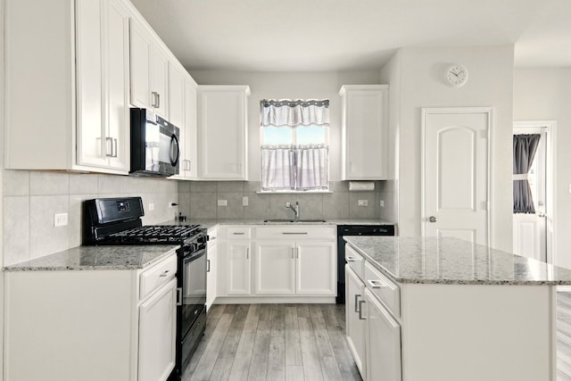 112 Black Alder St, Georgetown, TX 78626 - kitchen with black appliances, a sink, light wood-style flooring, a center island, and white cabinetry
