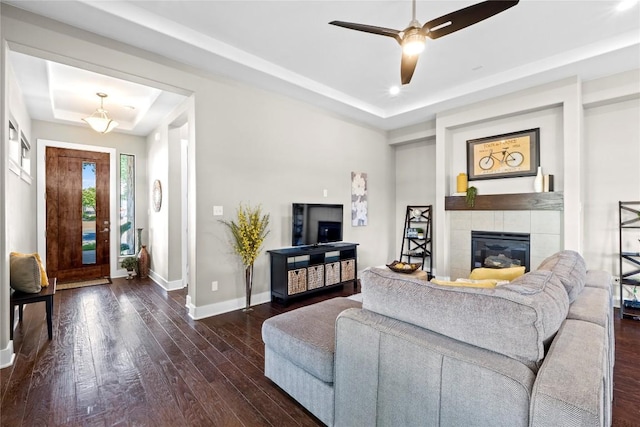 1017 Sue Ann Rose Dr, Austin, TX 78717 - living area featuring a raised ceiling, baseboards, dark wood-type flooring, a tiled fireplace, and ceiling fan