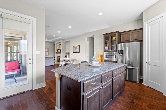 1017 Sue Ann Rose Dr, Austin, TX 78717 - kitchen featuring stainless steel appliances, dark wood finished floors, a center island, dark brown cabinets, and light stone countertops