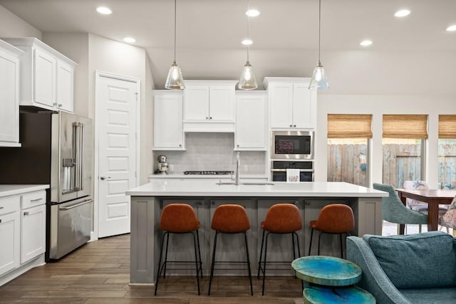 18621 James Power Ct, Austin, TX 78738 - kitchen featuring appliances with stainless steel finishes, a sink, backsplash, a breakfast bar, and recessed lighting