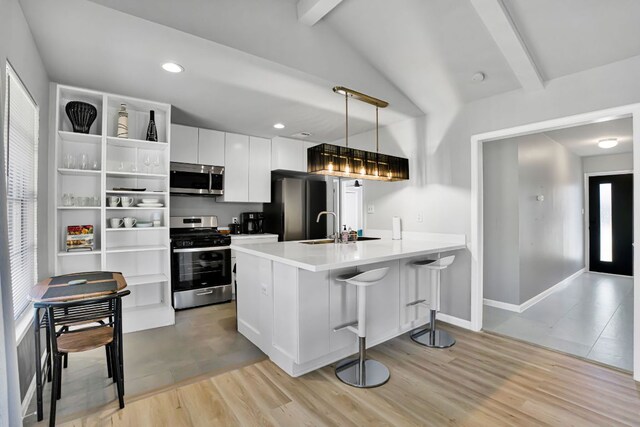 1205 Arthur Stiles Rd, Austin, TX 78721 - kitchen featuring appliances with stainless steel finishes, white cabinetry, a kitchen bar, a sink, and light wood-style floors