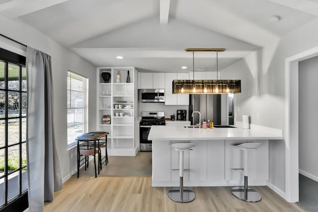 1205 Arthur Stiles Rd, Austin, TX 78721 - kitchen with appliances with stainless steel finishes, a peninsula, light wood-type flooring, white cabinetry, and a kitchen breakfast bar