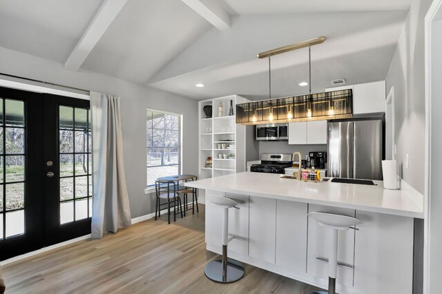 1205 Arthur Stiles Rd, Austin, TX 78721 - kitchen with stainless steel appliances, french doors, a peninsula, white cabinetry, and a breakfast bar area