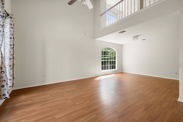 12303 Shropshire Blvd, Austin, TX 78753 - unfurnished room with light wood-style floors, ceiling fan, a towering ceiling, and baseboards