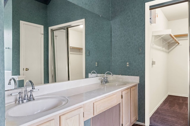 12303 Shropshire Blvd, Austin, TX 78753 - bathroom with double vanity, a walk in closet, and baseboards