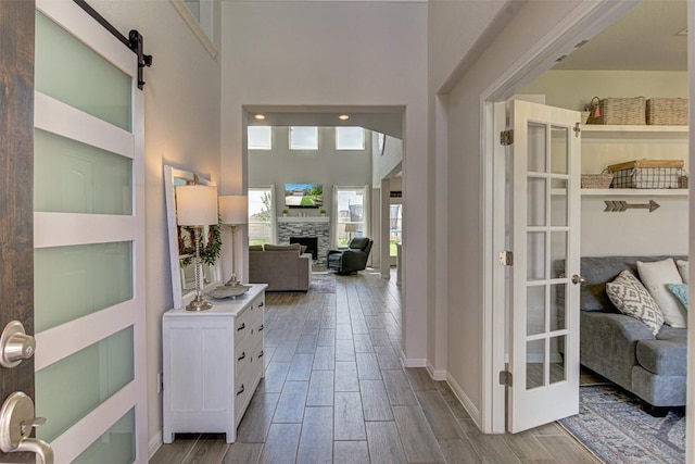 20517 Kangal Ct, Pflugerville, TX 78660 - entrance foyer featuring a stone fireplace, wood finish floors, a towering ceiling, baseboards, and a barn door