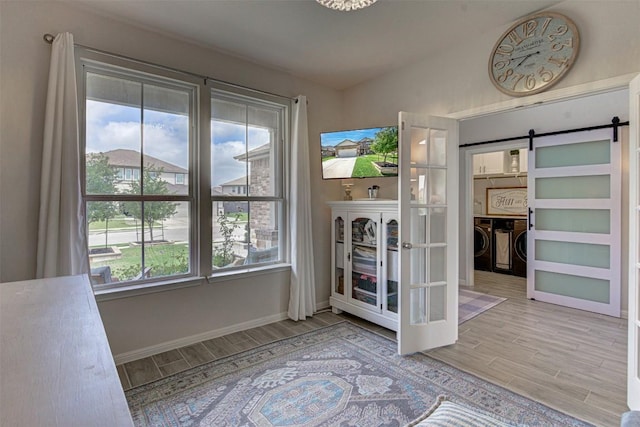 20517 Kangal Ct, Pflugerville, TX 78660 - doorway with separate washer and dryer, a barn door, wood finished floors, baseboards, and vaulted ceiling
