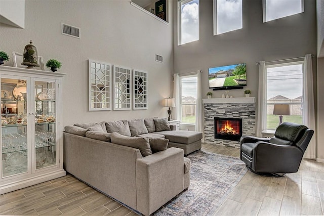 20517 Kangal Ct, Pflugerville, TX 78660 - living room featuring light wood-type flooring, a lit fireplace, and a towering ceiling
