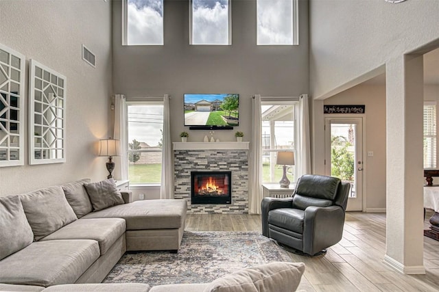 20517 Kangal Ct, Pflugerville, TX 78660 - living area with a stone fireplace, a high ceiling, wood finished floors, and healthy amount of natural light