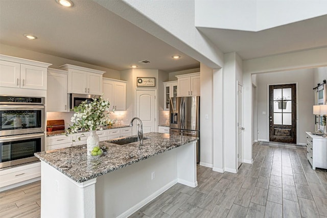 20517 Kangal Ct, Pflugerville, TX 78660 - kitchen featuring a sink, stainless steel appliances, white cabinetry, recessed lighting, and light stone counters
