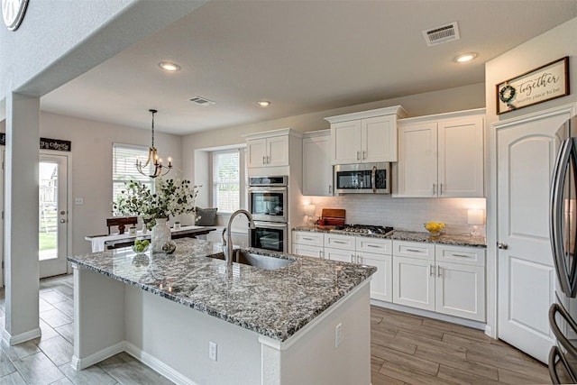 20517 Kangal Ct, Pflugerville, TX 78660 - kitchen with stainless steel appliances, a sink, white cabinets, decorative backsplash, and stone countertops