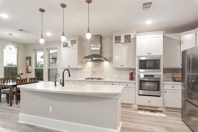 5400 Alonso Dr, Austin, TX 78738 - kitchen featuring stainless steel appliances, wall chimney exhaust hood, light countertops, a sink, and light wood finished floors