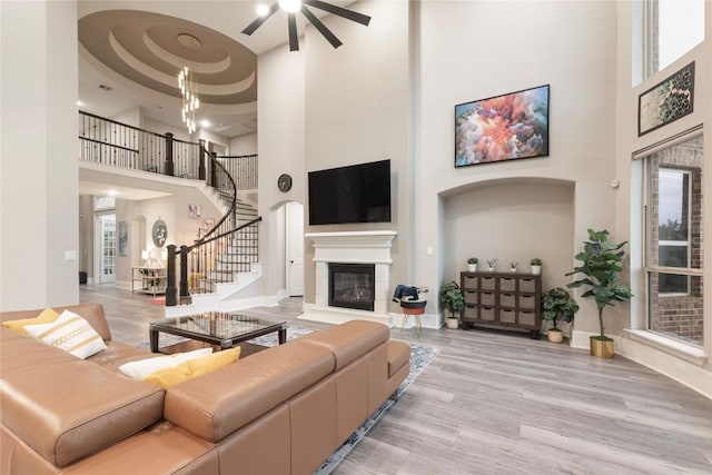5400 Alonso Dr, Austin, TX 78738 - living room featuring a towering ceiling, ceiling fan, stairs, a glass covered fireplace, and wood finished floors