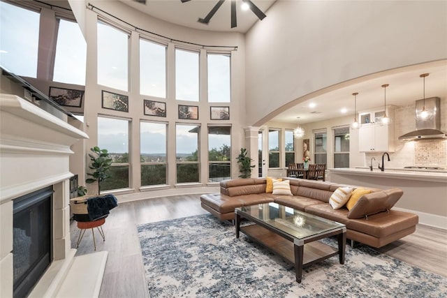 5400 Alonso Dr, Austin, TX 78738 - living area featuring arched walkways, a glass covered fireplace, a ceiling fan, wood finished floors, and healthy amount of natural light