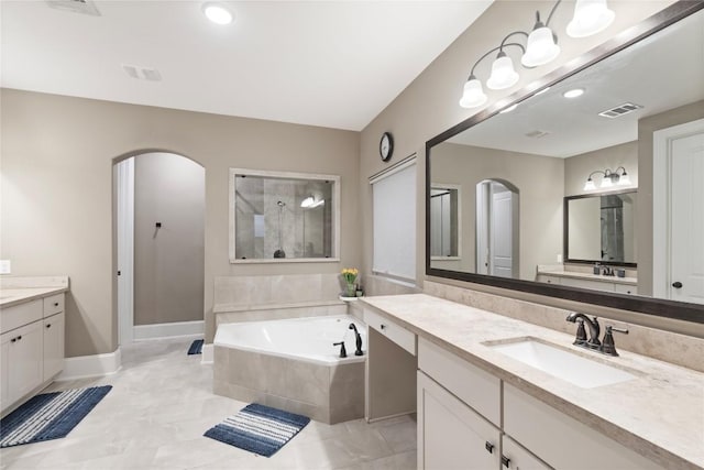 5400 Alonso Dr, Austin, TX 78738 - bathroom featuring two vanities, a garden tub, walk in shower, baseboards, and tile patterned flooring