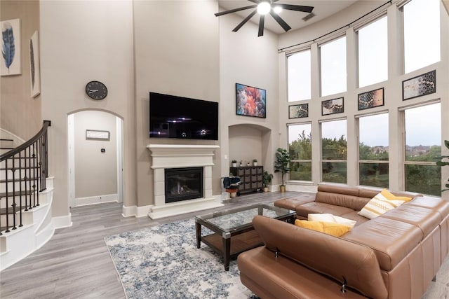 5400 Alonso Dr, Austin, TX 78738 - living room with a high ceiling, ceiling fan, a glass covered fireplace, wood finished floors, and stairway
