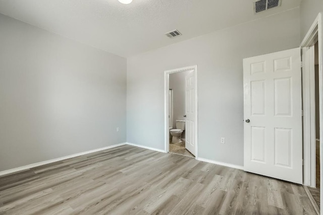 9008 Tall Sky Trce, Austin, TX 78724 - unfurnished bedroom with wood finished floors, baseboards, and ensuite bathroom