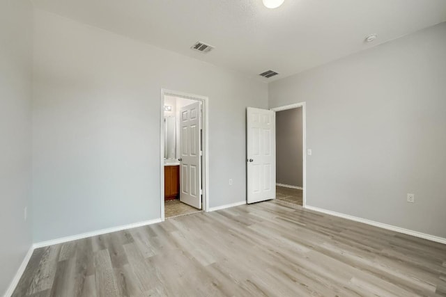 9008 Tall Sky Trce, Austin, TX 78724 - unfurnished bedroom with light wood-type flooring, baseboards, and ensuite bath