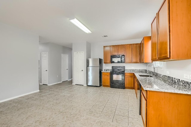9008 Tall Sky Trce, Austin, TX 78724 - kitchen with black appliances, a sink, brown cabinets, light stone counters, and baseboards