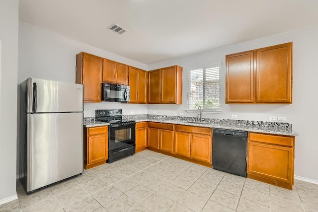 9008 Tall Sky Trce, Austin, TX 78724 - kitchen with black appliances, a sink, brown cabinetry, and light stone countertops